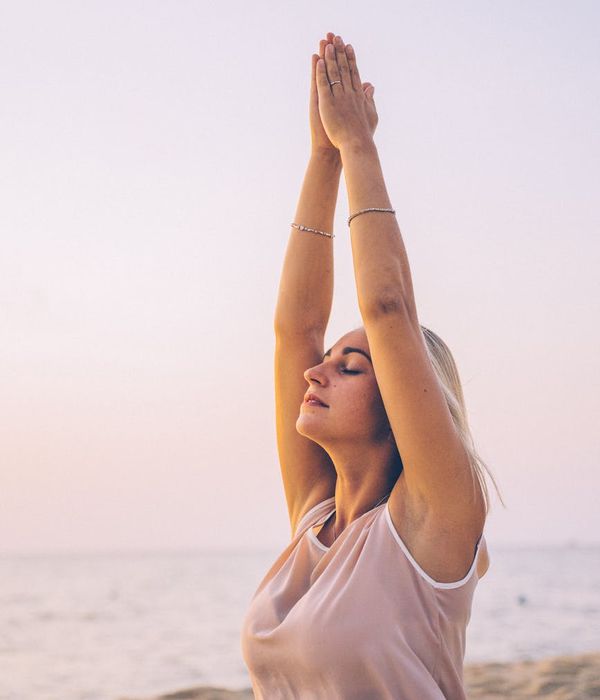 Woman feeling energized and stretching outdoors at sunrise.